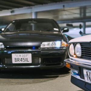 Classic modified cars in an Auckland parking lot, emphasizing car culture and customization.