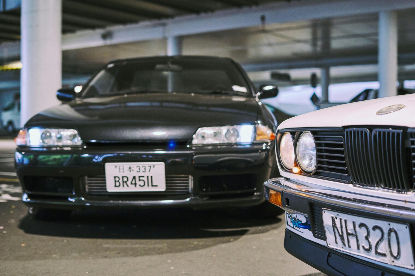 Classic modified cars in an Auckland parking lot, emphasizing car culture and customization.