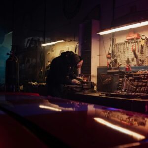 A mechanic diligently working on a car part in a tool-filled garage.